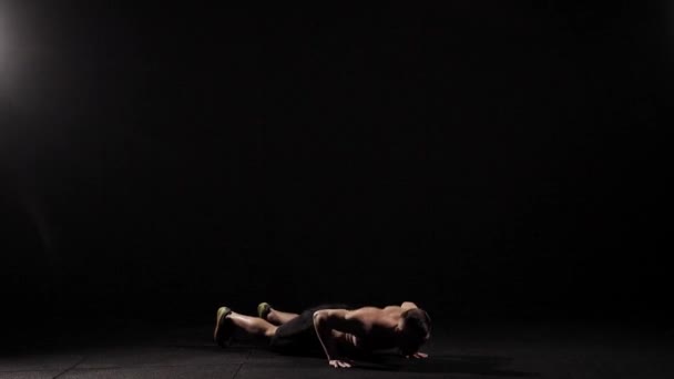Спортсмен тренируется в гимнастическом зале, лежа на полу и выполняя отжимания, затем встает, повторяя упражнения — стоковое видео