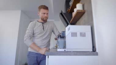 Adam mutfakta bir cam kap sıcak süzülmüş kahve bir fincan dökme.