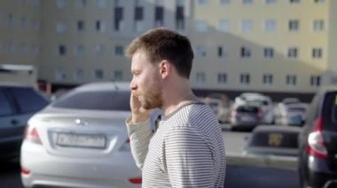 neşeli yetişkin adam cep telefonuyla konuşurken ve yürüyüş arasında arabaları park, onun otomobil sürücü koltuğu üzerinde oturan