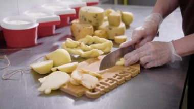 Taze peynir özel eldiven giymiş bir bıçak ile dilimleme bir peynir fabrikası işçisi.