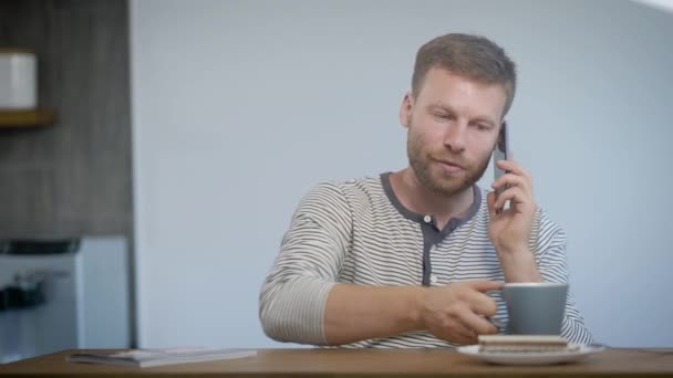 Hombre bebiendo y hablando en smartphone — Vídeos de Stock