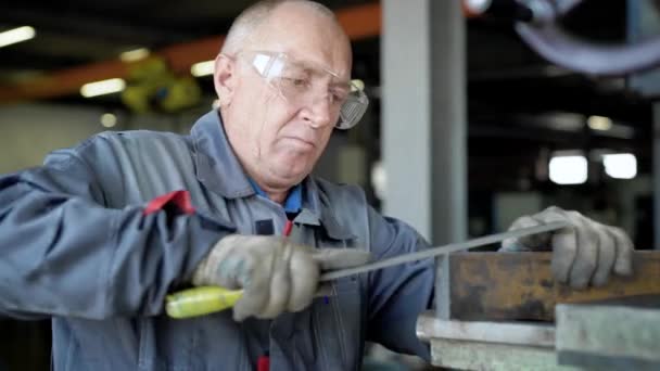 Um homem idoso em produção. O trabalhador terá um arquivo . — Vídeo de Stock