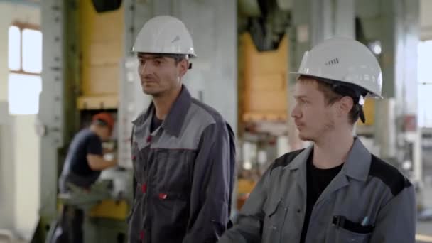 Dos trabajadores están en la sala de producción con grandes tornos . — Vídeos de Stock