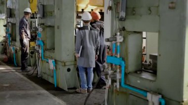 Büyük torna ile üretim koridorda iki işçi vardır.