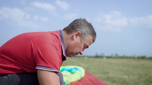 Tiro de close-up de um profissional arrumando um paraquedas em um campo vazio . — Vídeo de Stock
