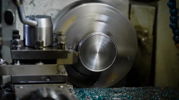 Round metal detail is rotating inside a grinding machine, blade is rubbing out a layer of metal and shaping — Stock Video