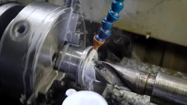 Metal detail is rotating around big drill of machine, perforating hole, cooling liquid is pouring on connection — Stock Video