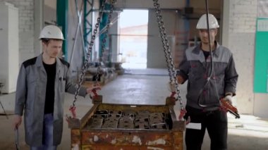 iki işçi bitmiş metal ayrıntılar, asılı kutusuyla atölye uzayda yürüyüş düzenliyoruz