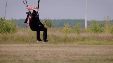 profesyonel skydiver güneşli bir günde bir alana iniş ve gölgelik paraşütü yere koyarak