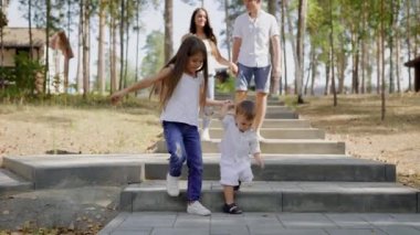 küçük kız bebek kardeşi birlikte taş merdiven bir parkta gündüzleri yürürken, el ele tutuşarak, arkasında ebeveyn are