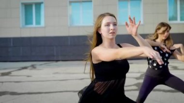 Grup üç kadın dansçıların büyük bir şehirde yaz akşamında, gövdeleri taşıma binanın bahçesinde dans ediyor