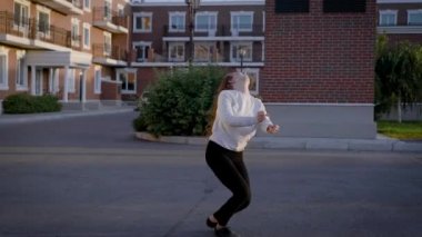Yalnız ince dansçı kız döne döne ve Bale pas gerçekleştirme günbatımı zamanında bir şehirde evlerin bir bahçede dans ediyor
