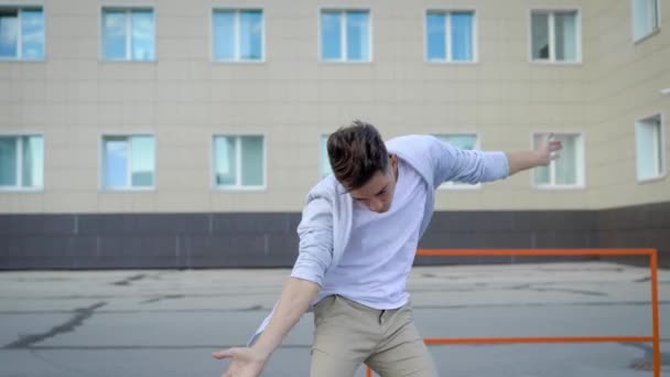 Joven bailarín está bailando en una calle en la ciudad en el día de verano, moviendo las manos hacia arriba y girando — Vídeo de stock