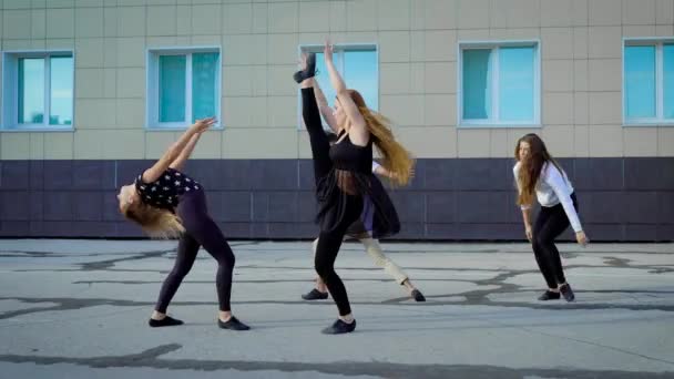 Четыре современных танцора репетируют современный танец на улице перед зданием днем — стоковое видео
