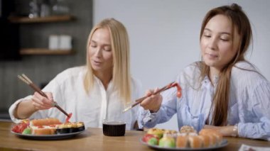 İki güzel kız evde Japon yemek yemek. Rulo bir plaka üzerinde farklı, çok lezzetli.