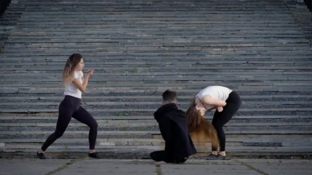 Bailarines contemporáneos haciendo un espectáculo al aire libre, dos chicas y un hombre bailando en la plaza . — Vídeos de Stock