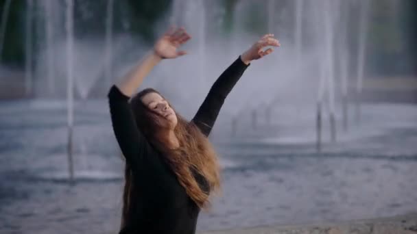 Beautiful active woman dancing jazz modern by the fountains in city. — Stock Video