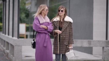 iki trendy ve şık kadın giyiyor kat şehir sokak üzerinde duran ve birbirinizle konuşmak
