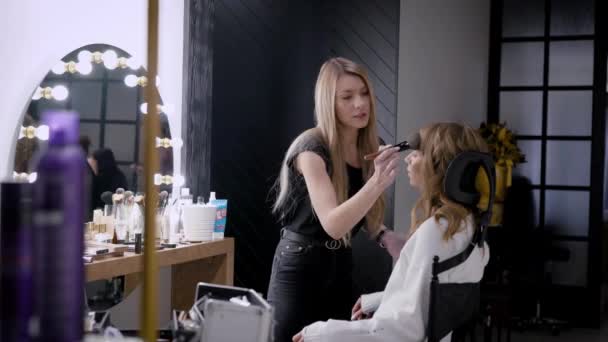 Proceso de maquillaje, la cara de una hermosa mujer joven y artistas de maquillaje mano con un cepillo y una esponja — Vídeo de stock