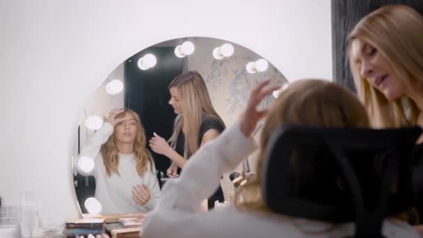 Processus de maquillage, le visage d'une belle jeune femme et maquilleurs main avec un pinceau et une éponge — Video