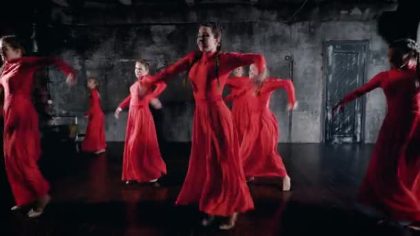 Modernes Ballett, dargeboten von sieben Tänzern. Mädchen in roten Kleidern führen synchron Tanzelemente auf — Stockvideo
