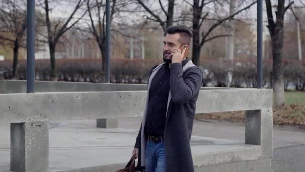 Jovem em desgaste casual falando no smartphone na rua — Vídeo de Stock