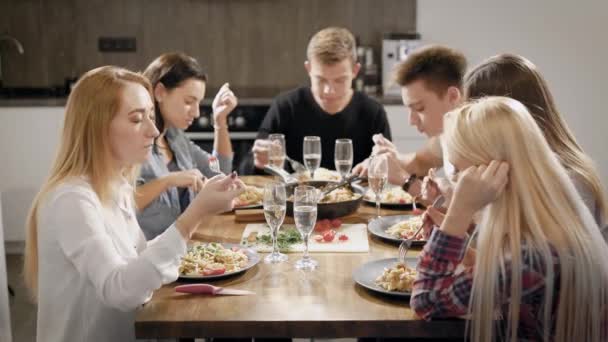 Jovens felizes jantando à mesa na cozinha — Vídeo de Stock