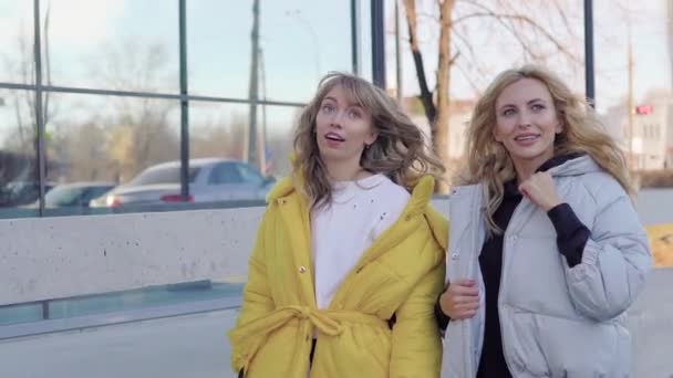 Mladé krásné usměvavé dámy v pláštích na ulici — Stock video