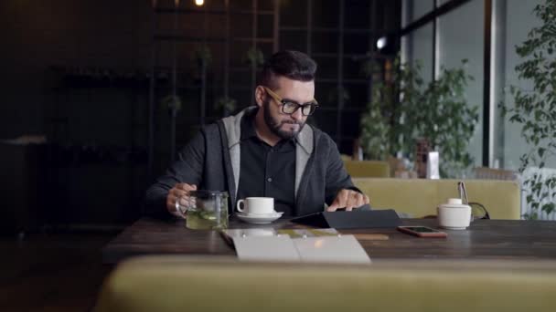 Ung man använder Tablet PC: n och dricka te i café — Stockvideo