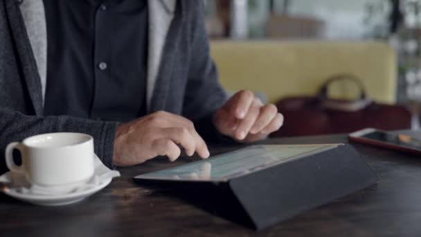 Jeune homme utilisant un ordinateur tablette et boire du thé dans le café — Video