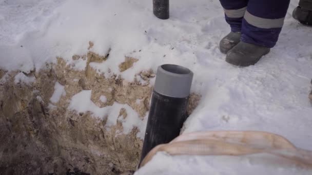 Im Rahmen eines in gefrorenem Boden ausgehobenen Grabens. Rohr aus Stahl und Kunststoff liegt im Graben. — Stockvideo