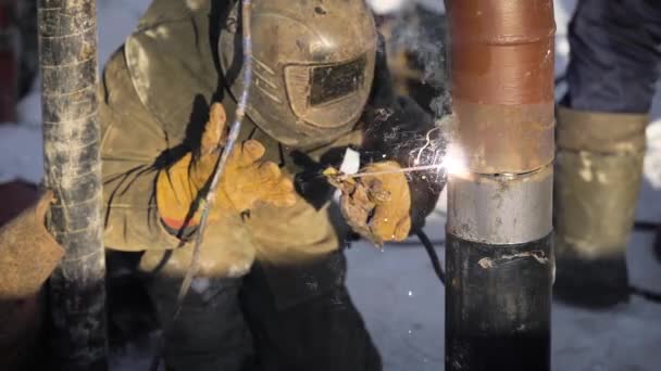 Trabalhador produz soldagem de tubos na rua. No inverno, a baixas temperaturas, é difícil montar o fio do tubo . — Vídeo de Stock