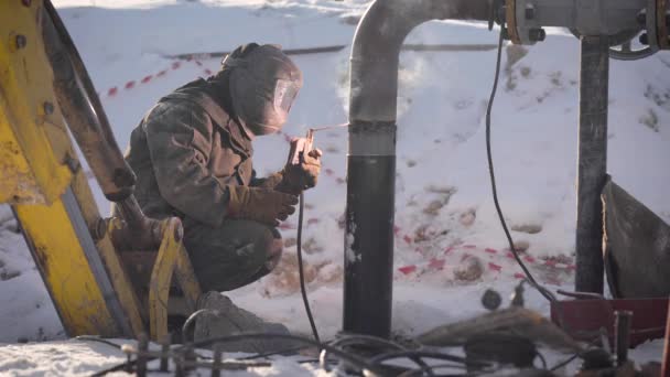 Arbeiter schweißt auf der Straße Rohre. im Winter ist es bei niedrigen Temperaturen schwierig, den Rohrdraht zu montieren. — Stockvideo