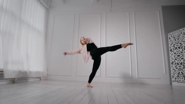 Chica rubia flexible practicando el baile en el interior de un estudio . — Vídeo de stock