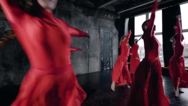 精力充沛的年轻女孩在红色舞蹈服装表演在演播室与黑色墙壁的团体舞蹈. — 图库视频影像