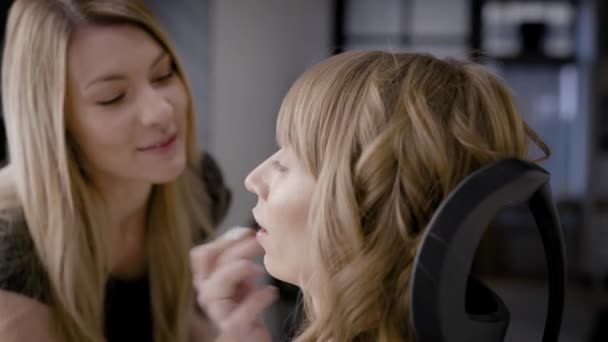 Gros plan d'un maquilleur faisant un maquillage professionnel sur une belle blonde, maquillage pour les vacances . — Video