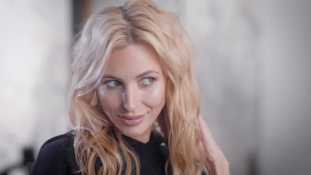 Attraktiv blond kvinna med vackra frisyr tittar på sig själv i en spegel efter skönhet sessioner. — Stockvideo