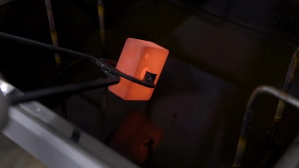 Arbeiter hält erhitztes Metall mit einer Pinzette und gibt es in kaltes Wasser zum Kühlen, Nahaufnahme — Stockvideo