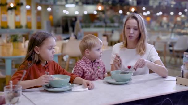 Uważać, że młoda matka karmi swojego synka przez spaghetti w kawiarni rodziny, Córka przedszkolak jest jedzenie — Wideo stockowe