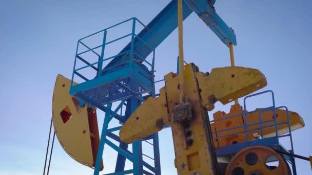 Průmyslové zařízení je čerpání ropy a zemního plynu ze země, nakloňte zobrazení proti modré obloze — Stock video