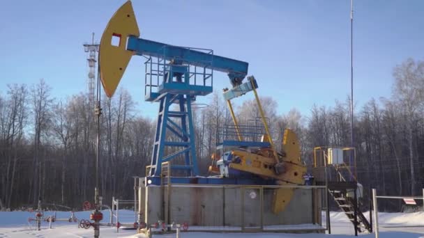 昼間の冬の森で働いている油の揚水、pumpjack は地面から石油やガスの汲み上げ — ストック動画