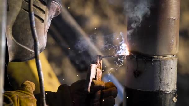 Travailleur soude des tuyaux en acier à l'extérieur pendant la journée sur un puits d'huile, portant un masque de protection et des gants — Video