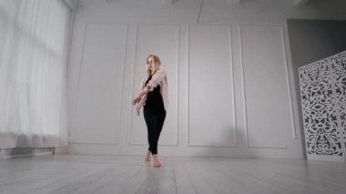 sarışın kadın çağdaş performans, eğitim salonunda gündüz bacaklar yukarı ve iplik yükselen tek başına dans ediyor