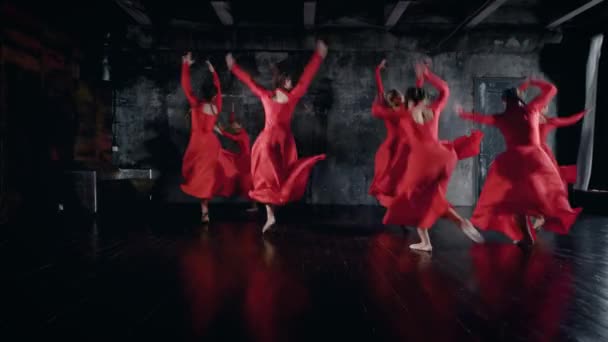 Meninas adolescentes estão realizando dança em uma sala de ensaio, vestindo vestidos vermelhos, pulando e girando — Vídeo de Stock