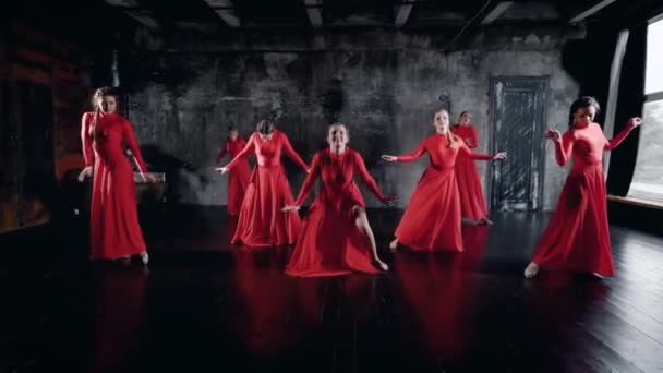 Siete bailarinas encantadoras están bailando en la sala de ensayo, vistiendo vestidos rojos, tumbadas en el suelo — Vídeo de stock