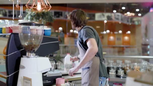 Barista profesional de pie junto al mostrador y haciendo un café . — Vídeo de stock