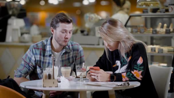 Ritratto di una bella coppia in un caffè, fidanzato e fidanzata in un appuntamento in un accogliente caffè mangiare dolci e bere caffè . — Video Stock