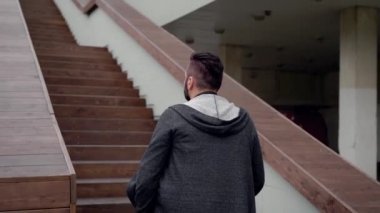 Gri kapşonlu bir restoran merdivenlerde yürürken şık brunet yetişkin adam.