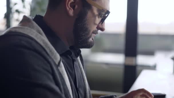 Gros plan d'un gars bavardant en ligne sur une tablette dans un café, tasse de thé sur la table . — Video