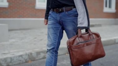 Yakışıklı adam tek başına, sessiz yürüyüş yürüyüş kahverengi deri çanta.